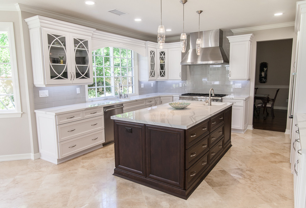 Large modern u-shaped eat-in kitchen in Los Angeles with a double-bowl sink, shaker cabinets, white cabinets, quartz benchtops, grey splashback, subway tile splashback, stainless steel appliances, travertine floors and multiple islands.