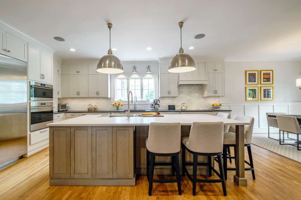 Eat-in kitchen - large transitional galley medium tone wood floor and brown floor eat-in kitchen idea with an undermount sink, shaker cabinets, white cabinets, quartz countertops, white backsplash, marble backsplash, stainless steel appliances, an island and white countertops