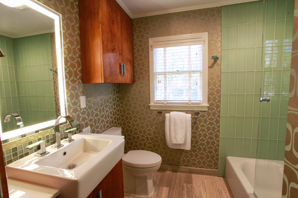 Photo of a small contemporary master bathroom in Houston with flat-panel cabinets, medium wood cabinets, engineered quartz benchtops, an alcove tub, a shower/bathtub combo, a one-piece toilet, green tile, glass tile, green walls and limestone floors.