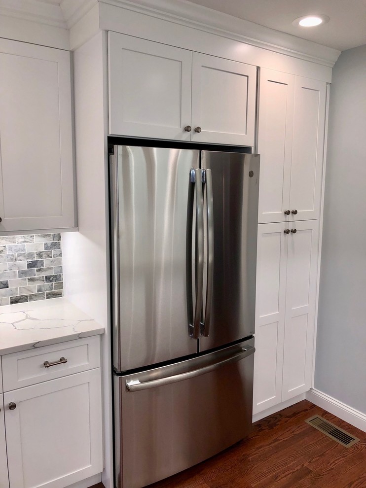 Inspiration for a mid-sized transitional u-shaped dark wood floor and brown floor enclosed kitchen remodel with an undermount sink, shaker cabinets, white cabinets, marble countertops, gray backsplash, stone tile backsplash, stainless steel appliances, no island and white countertops