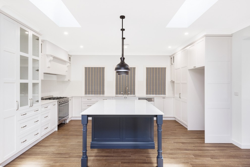 Expansive country u-shaped kitchen pantry in Canberra - Queanbeyan with a double-bowl sink, white cabinets, granite benchtops, white splashback, glass tile splashback, stainless steel appliances, vinyl floors, with island and white benchtop.