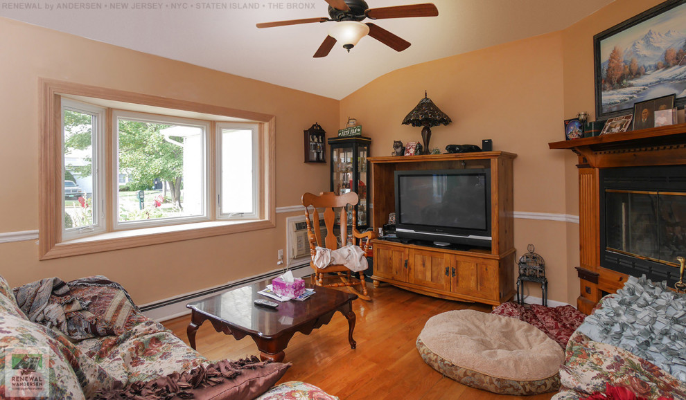 На фото: изолированная гостиная комната среднего размера с оранжевыми стенами, паркетным полом среднего тона, угловым камином, фасадом камина из дерева, отдельно стоящим телевизором и сводчатым потолком