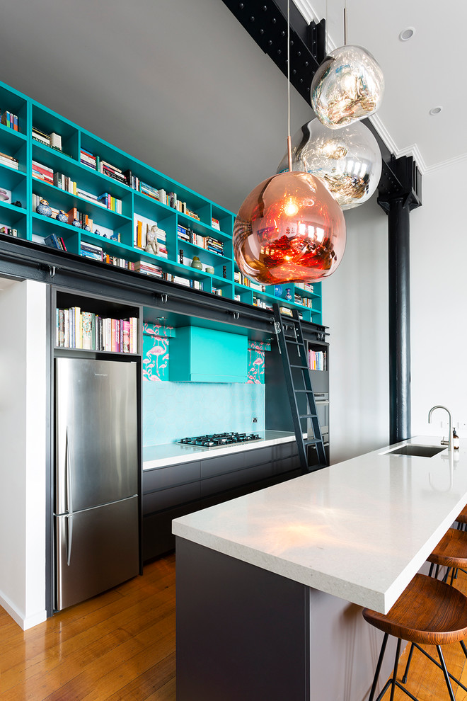 Inspiration for a mid-sized industrial galley eat-in kitchen in Melbourne with an undermount sink, flat-panel cabinets, grey cabinets, quartz benchtops, blue splashback, ceramic splashback, stainless steel appliances, medium hardwood floors and with island.
