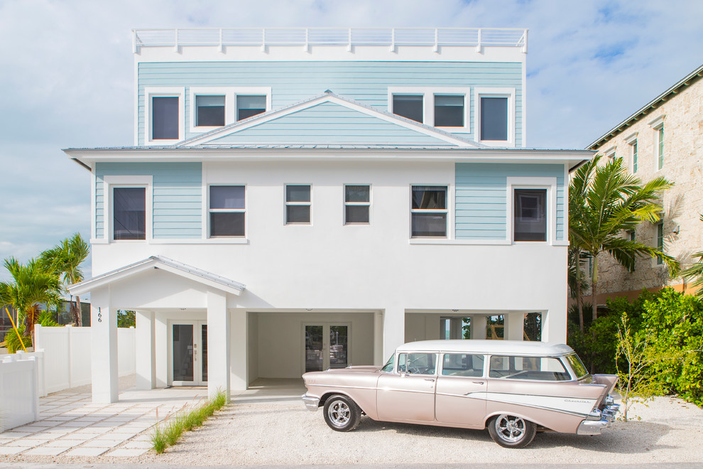 Inspiration for a large beach style three-storey concrete blue house exterior in Miami with a flat roof and a metal roof.