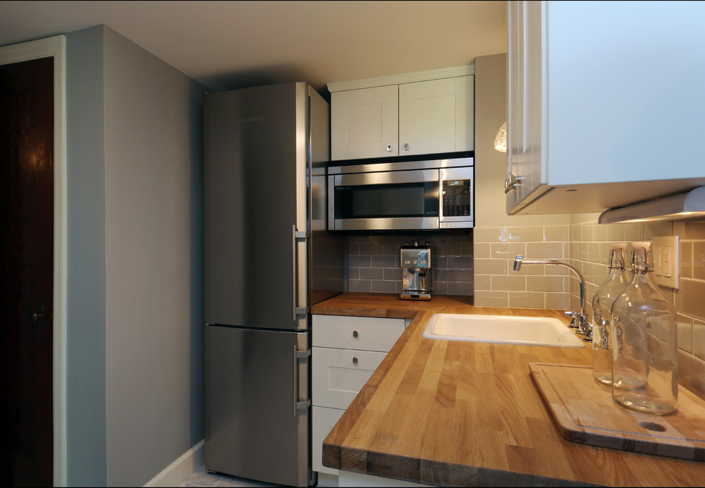This is an example of a small transitional l-shaped separate kitchen in Portland with a single-bowl sink, recessed-panel cabinets, white cabinets, wood benchtops, grey splashback, subway tile splashback, stainless steel appliances, marble floors and no island.