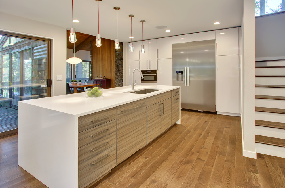 Mid-sized contemporary l-shaped separate kitchen in Seattle with an undermount sink, flat-panel cabinets, white cabinets, quartz benchtops, beige splashback, glass tile splashback, stainless steel appliances, medium hardwood floors and with island.