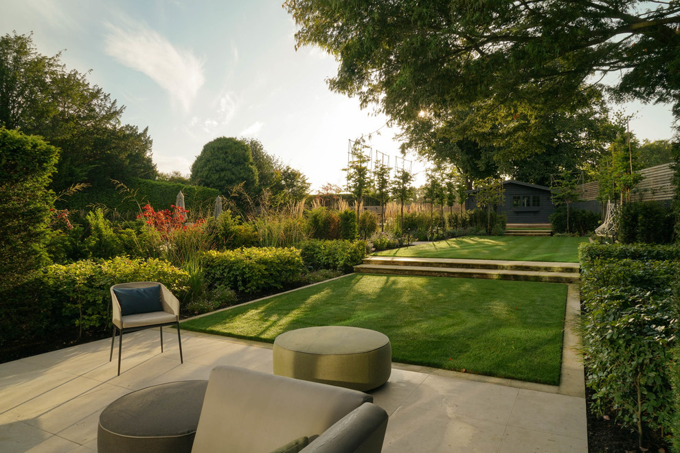 Large contemporary backyard formal garden in London with concrete pavers.