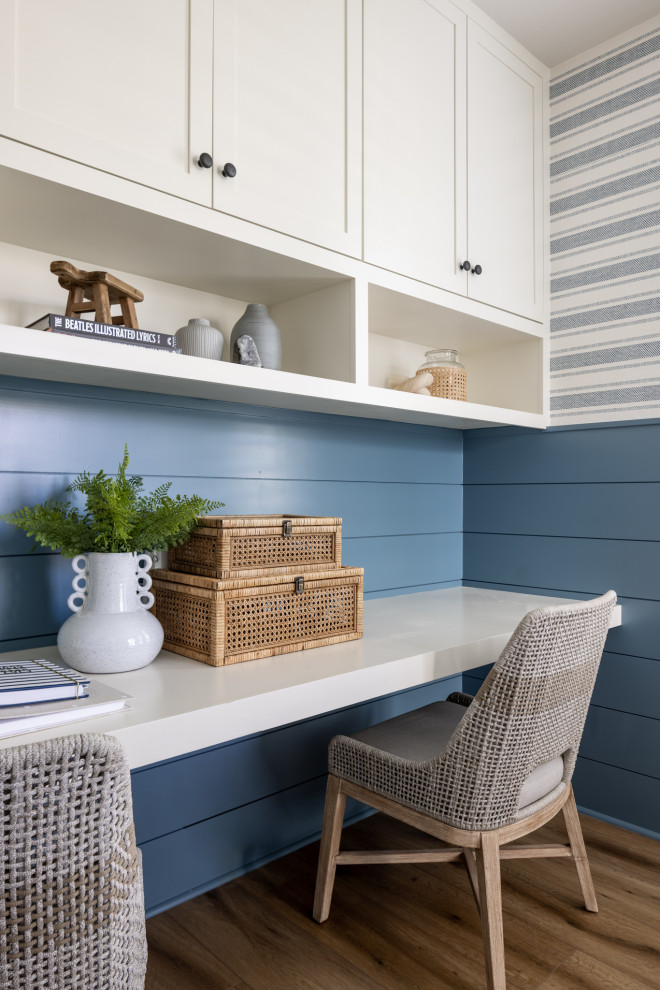 Inspiration for a coastal built-in desk medium tone wood floor, brown floor and shiplap wall home office remodel with blue walls