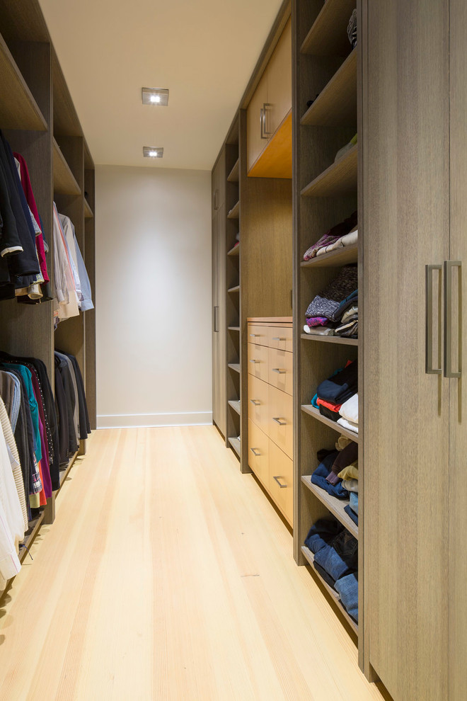 Small contemporary gender-neutral walk-in wardrobe in Minneapolis with open cabinets, medium wood cabinets, light hardwood floors and brown floor.