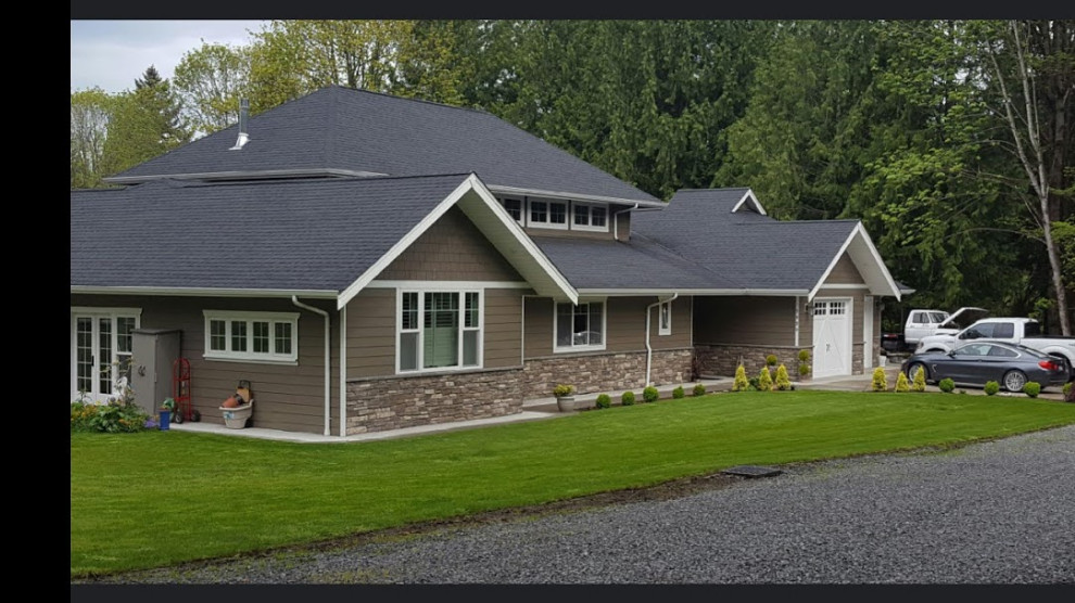 This is an example of a large arts and crafts one-storey beige house exterior in Seattle with vinyl siding, a gable roof and a shingle roof.