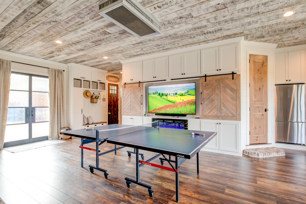 Farmhouse porcelain tile and brown floor game room photo in Dallas with white walls, a ribbon fireplace, a wood fireplace surround and a media wall