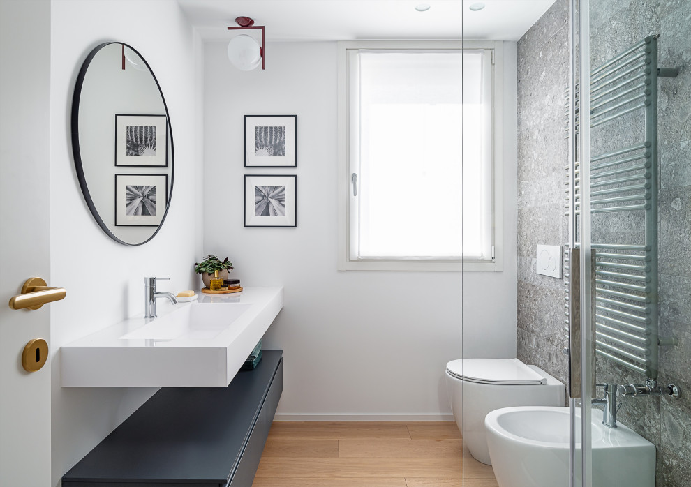 Modern inredning av ett litet vit vitt badrum med dusch, med släta luckor, grå skåp, en hörndusch, vita väggar, ljust trägolv, ett integrerad handfat, bänkskiva i akrylsten och dusch med gångjärnsdörr