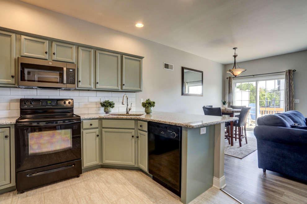 Example of a mid-sized transitional u-shaped vinyl floor and gray floor eat-in kitchen design with an undermount sink, recessed-panel cabinets, green cabinets, granite countertops, white backsplash, subway tile backsplash, black appliances, a peninsula and gray countertops