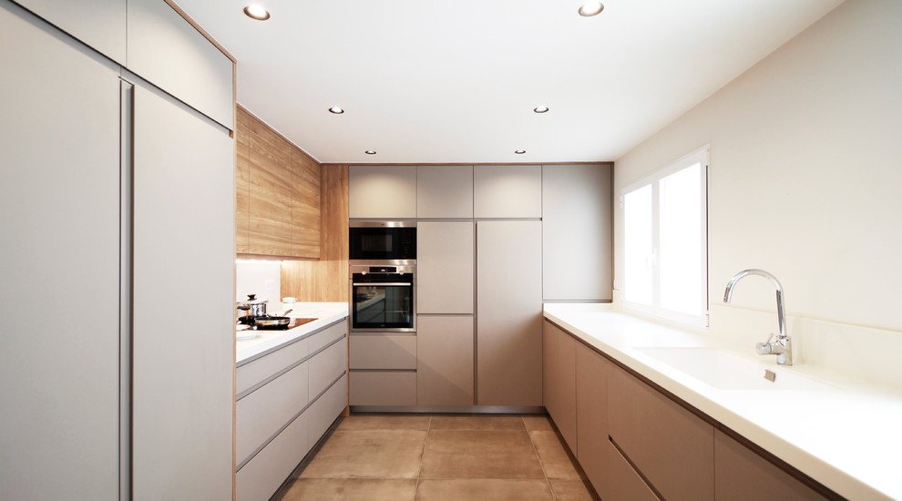 Large modern u-shaped separate kitchen in Other with an integrated sink, flat-panel cabinets, grey cabinets, white splashback, no island, white benchtop, panelled appliances, concrete floors and beige floor.