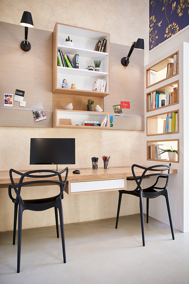 Photo of a mid-sized eclectic home office in Nantes with a library, beige walls, concrete floors, a built-in desk and grey floor.