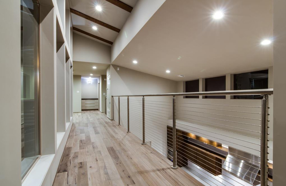This is an example of a large transitional hallway in Houston with grey walls, light hardwood floors and grey floor.