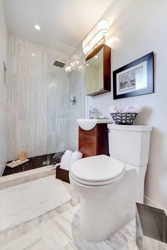 This is an example of a small contemporary 3/4 bathroom in DC Metro with recessed-panel cabinets, dark wood cabinets, an open shower, a one-piece toilet, white tile, marble, grey walls, marble floors, a wall-mount sink, white floor and an open shower.