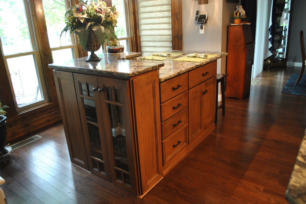 Kitchen - brown floor kitchen idea with brown cabinets, beige backsplash, stainless steel appliances, an island and gray countertops