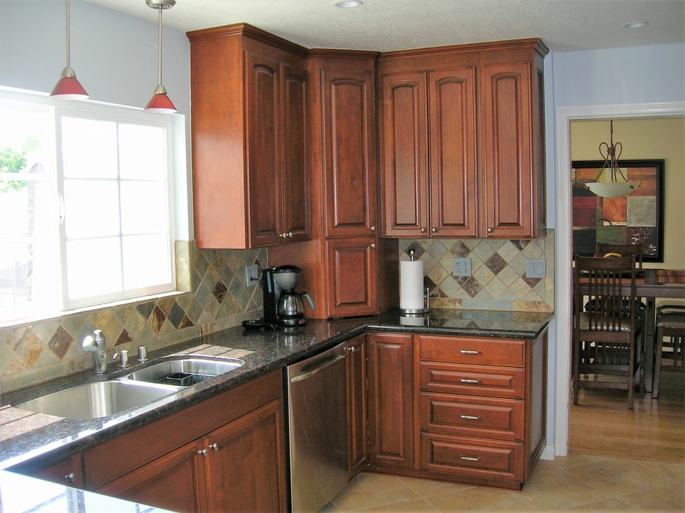 Mid-sized traditional l-shaped open plan kitchen in Los Angeles with an undermount sink, raised-panel cabinets, granite benchtops, multi-coloured splashback, slate splashback, stainless steel appliances, ceramic floors, a peninsula, multi-coloured floor, multi-coloured benchtop and medium wood cabinets.