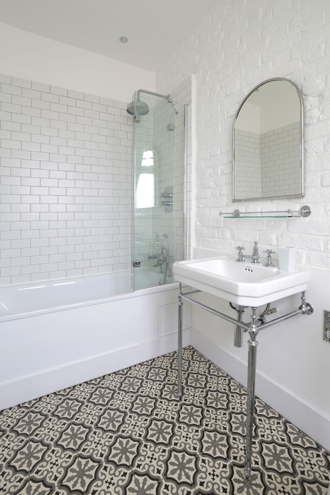 Mid-sized mediterranean bathroom in London with a shower/bathtub combo, ceramic floors, a console sink, subway tile, white walls and black and white tile.