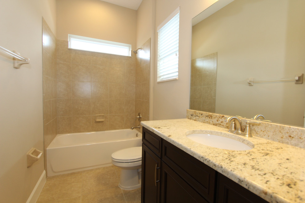 Large transitional kids bathroom in Orlando with recessed-panel cabinets, dark wood cabinets, an alcove tub, a shower/bathtub combo, a one-piece toilet, beige tile, porcelain tile, beige walls, ceramic floors, an undermount sink, granite benchtops, beige floor, a shower curtain, beige benchtops, a shower seat, a single vanity and a built-in vanity.