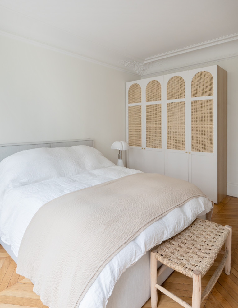 Idée de décoration pour une grande chambre parentale beige et blanche nordique avec un mur blanc, parquet clair et dressing.