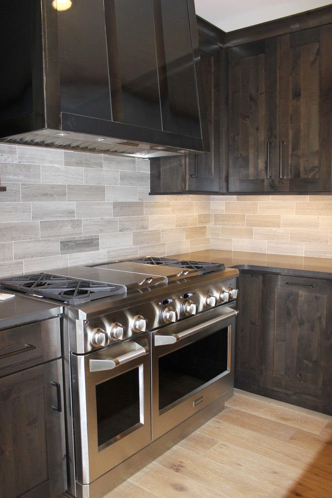 Mountain style light wood floor kitchen photo in Cedar Rapids with shaker cabinets, dark wood cabinets, zinc countertops, gray backsplash, porcelain backsplash and stainless steel appliances