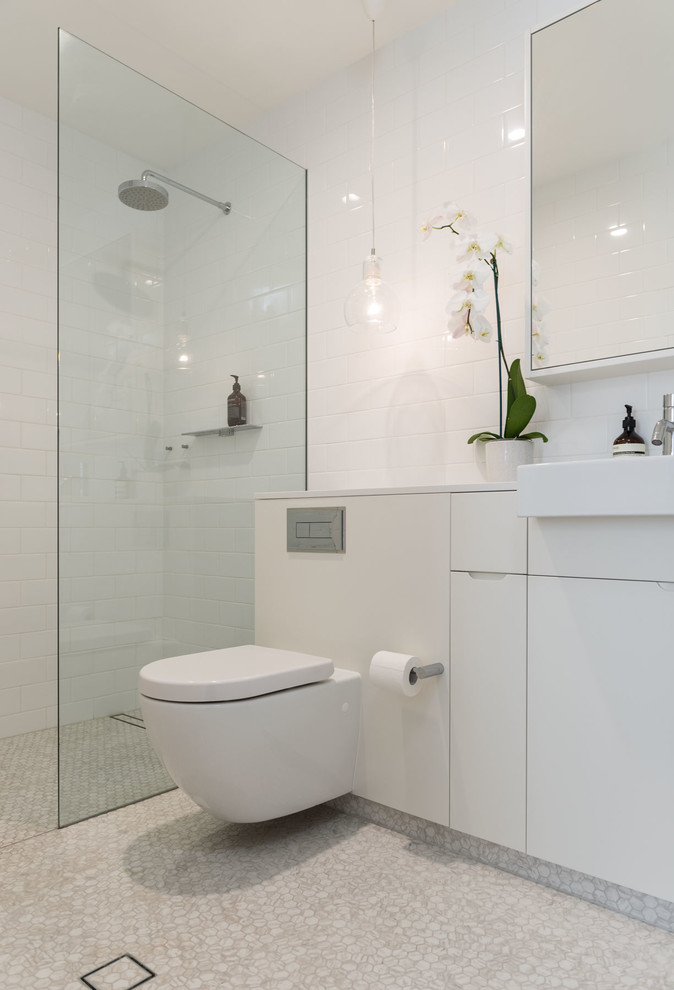 Photo of a small contemporary bathroom in Sydney with an open shower, a wall-mount toilet, white tile, ceramic tile, white walls, mosaic tile floors, an integrated sink and engineered quartz benchtops.