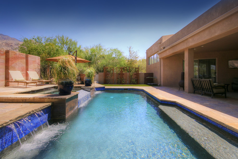 This is an example of a large country backyard custom-shaped pool in Phoenix with concrete pavers and a water feature.