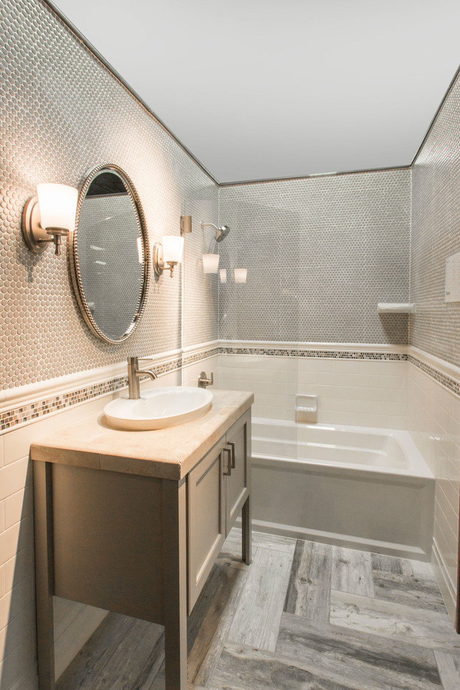Photo of a bathroom in Houston with shaker cabinets, beige cabinets, a shower/bathtub combo, gray tile, grey walls, ceramic floors and a vessel sink.