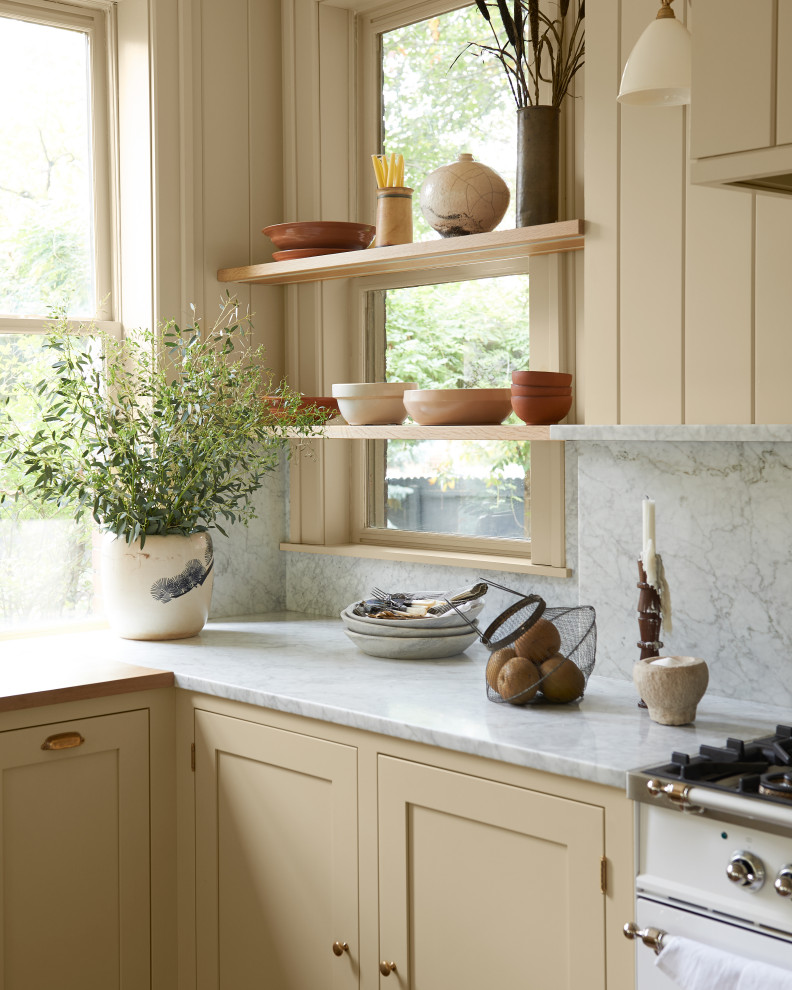 Foto på ett mellanstort vintage grå kök och matrum, med skåp i shakerstil, gula skåp, marmorbänkskiva, grått stänkskydd, stänkskydd i marmor, vita vitvaror, mellanmörkt trägolv och brunt golv