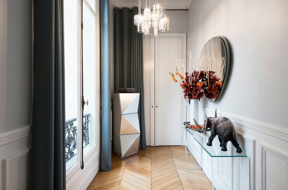 Photo of a mid-sized eclectic hallway in Paris with grey walls and medium hardwood floors.