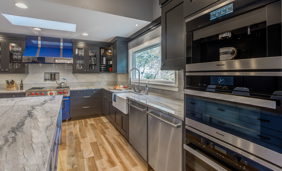 Large transitional u-shaped light wood floor eat-in kitchen photo in Denver with a farmhouse sink, recessed-panel cabinets, gray cabinets, quartzite countertops, blue backsplash, ceramic backsplash, stainless steel appliances and an island