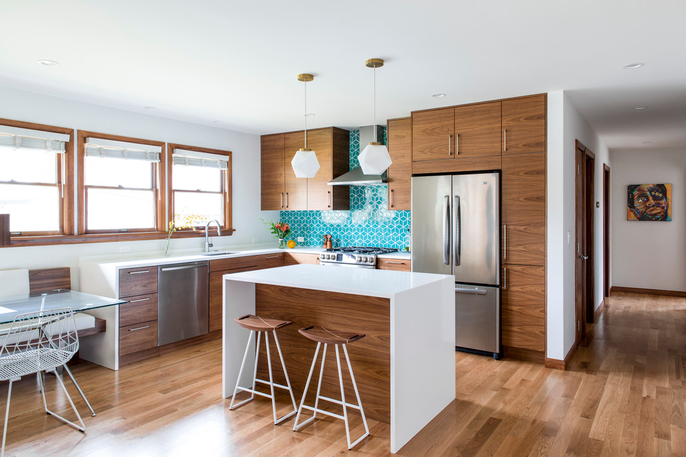 Eat-in kitchen - mid-sized mid-century modern l-shaped medium tone wood floor eat-in kitchen idea in Portland with an undermount sink, flat-panel cabinets, quartz countertops, blue backsplash, ceramic backsplash, stainless steel appliances, an island and medium tone wood cabinets