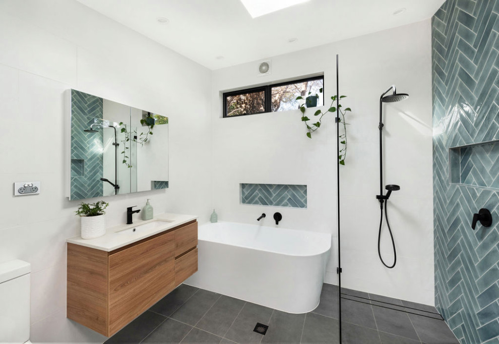 This is an example of a medium sized contemporary family bathroom in Canberra - Queanbeyan with freestanding cabinets, medium wood cabinets, a walk-in shower, a one-piece toilet, white tiles, ceramic tiles, white walls, ceramic flooring, a submerged sink, engineered stone worktops, grey floors, an open shower, white worktops, a wall niche, a single sink and a floating vanity unit.
