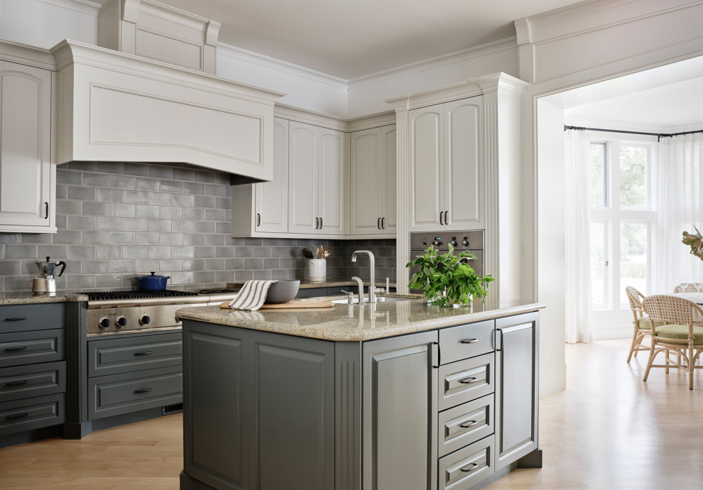 Inspiration for a huge timeless light wood floor and brown floor enclosed kitchen remodel in San Francisco with an undermount sink, raised-panel cabinets, gray cabinets, granite countertops, gray backsplash, ceramic backsplash, stainless steel appliances, beige countertops and an island