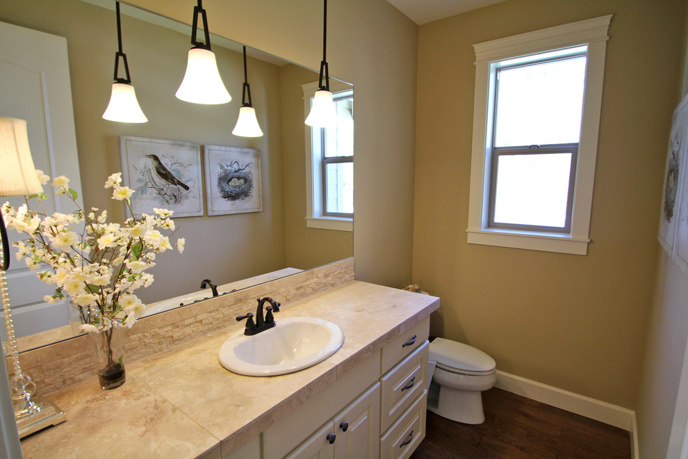 Photo of a mid-sized traditional bathroom in Portland with raised-panel cabinets, beige cabinets, a one-piece toilet, beige tile, stone tile, beige walls, dark hardwood floors, a drop-in sink and tile benchtops.