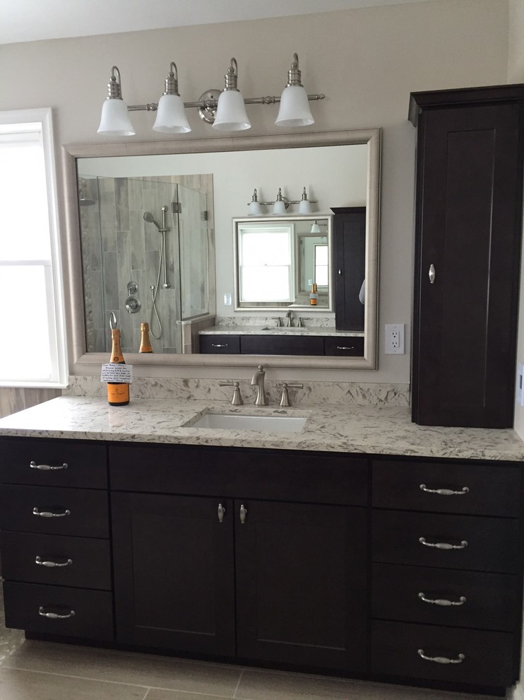 Large transitional master gray tile and porcelain tile light wood floor and brown floor freestanding bathtub photo in Baltimore with shaker cabinets, dark wood cabinets, a two-piece toilet, beige walls, an undermount sink, solid surface countertops and a hinged shower door