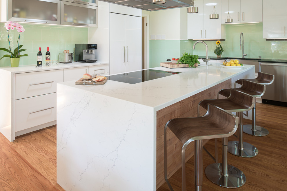 Design ideas for a large contemporary u-shaped eat-in kitchen in Indianapolis with a farmhouse sink, flat-panel cabinets, white cabinets, marble benchtops, green splashback, glass sheet splashback, panelled appliances, medium hardwood floors, with island and brown floor.