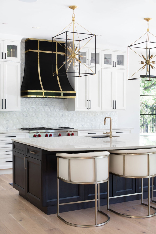 Large transitional l-shaped open plan kitchen in Austin with shaker cabinets, white cabinets, quartzite benchtops, white splashback, marble splashback, stainless steel appliances, light hardwood floors, with island and white benchtop.