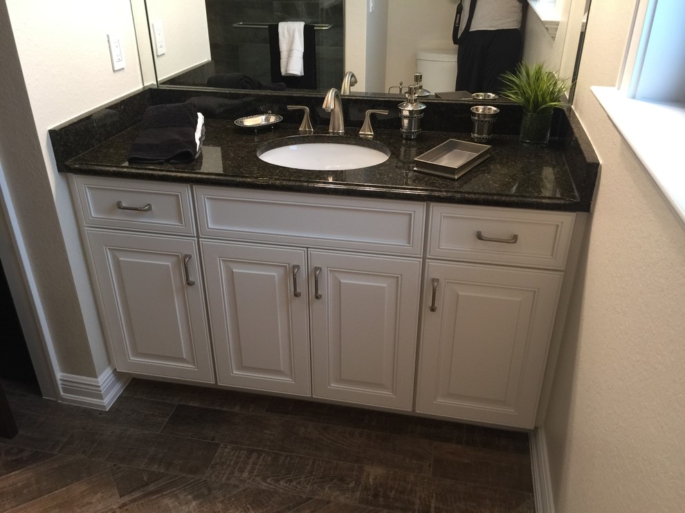 Photo of a mid-sized transitional master bathroom in Miami with an undermount sink, raised-panel cabinets, white cabinets, granite benchtops, a freestanding tub, an open shower, a one-piece toilet, beige walls and medium hardwood floors.