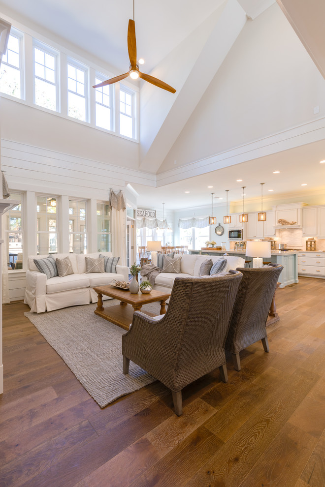 Photo of a large beach style open concept family room in Other with white walls, medium hardwood floors, a standard fireplace, a stone fireplace surround, a built-in media wall and white floor.