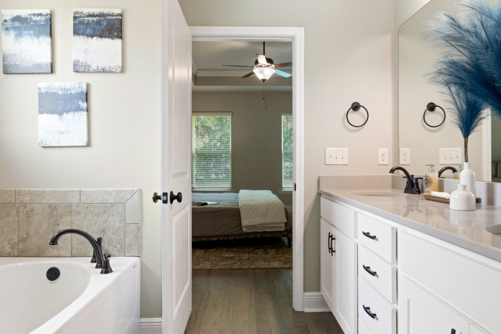 This is an example of a mid-sized traditional master bathroom in Other with white cabinets, an alcove tub, beige tile, beige walls, granite benchtops, brown floor, grey benchtops, a double vanity and a built-in vanity.