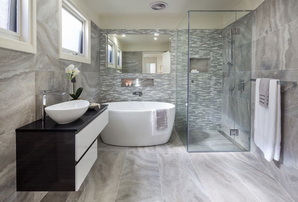 Design ideas for a mid-sized contemporary 3/4 bathroom in Melbourne with a freestanding tub, a corner shower, a two-piece toilet, gray tile, porcelain tile, grey walls, porcelain floors, a vessel sink and granite benchtops.