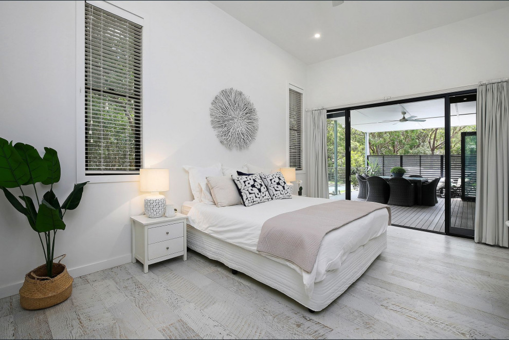 Large contemporary master bedroom in Central Coast with laminate floors, white walls and grey floor.