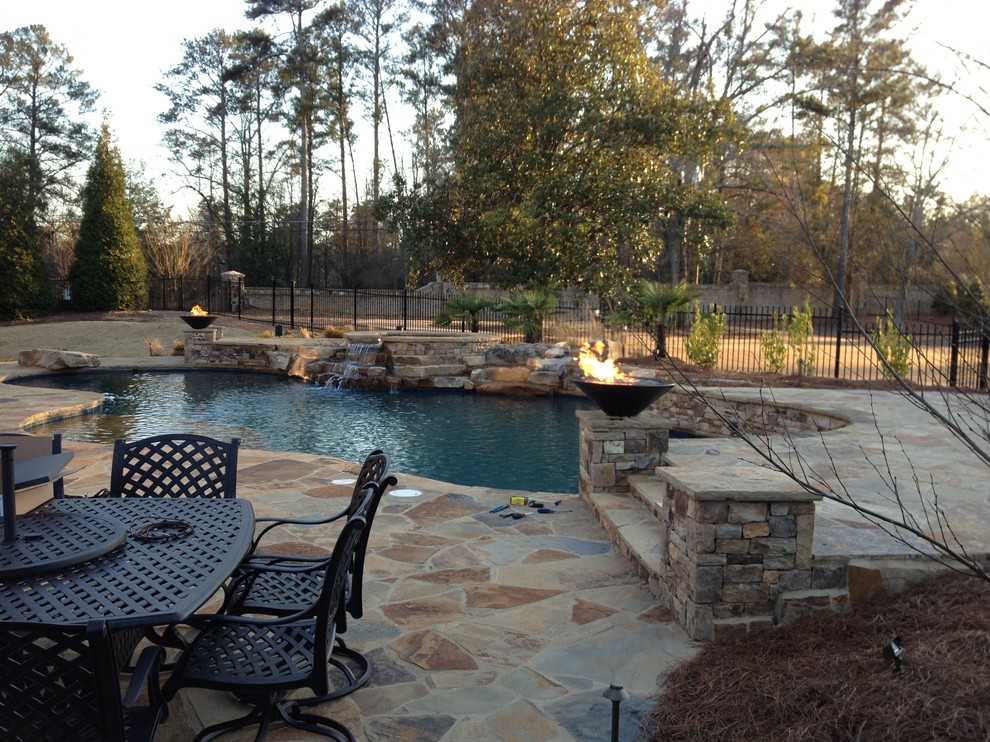 This is an example of a large traditional backyard custom-shaped lap pool in Atlanta with a hot tub and natural stone pavers.