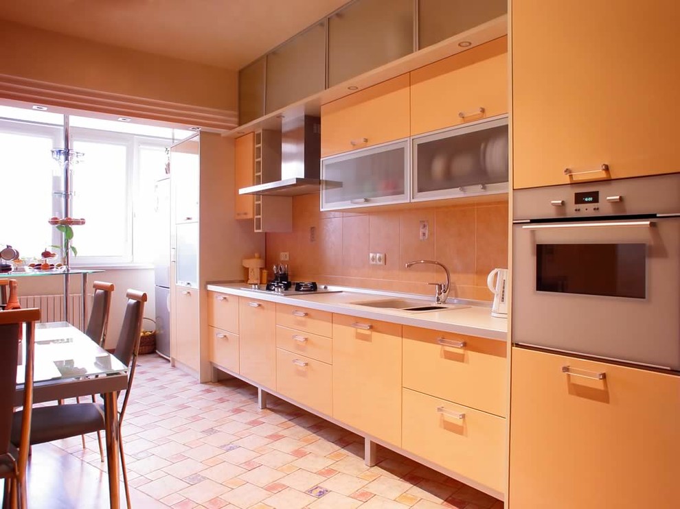 Eat-in kitchen - mid-sized transitional single-wall eat-in kitchen idea in Phoenix with a single-bowl sink, flat-panel cabinets, yellow cabinets, beige backsplash, stainless steel appliances and no island