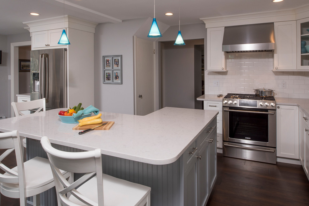 Kitchen - transitional l-shaped dark wood floor and brown floor kitchen idea in Boston with a farmhouse sink, flat-panel cabinets, white cabinets, quartz countertops, white backsplash, ceramic backsplash, stainless steel appliances and an island