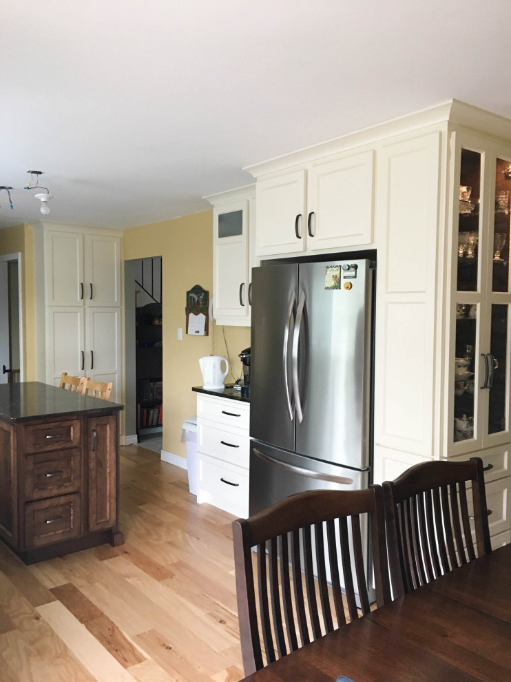 Mid-sized transitional galley light wood floor and beige floor eat-in kitchen photo with an undermount sink, shaker cabinets, white cabinets, quartz countertops, stainless steel appliances, an island and black countertops