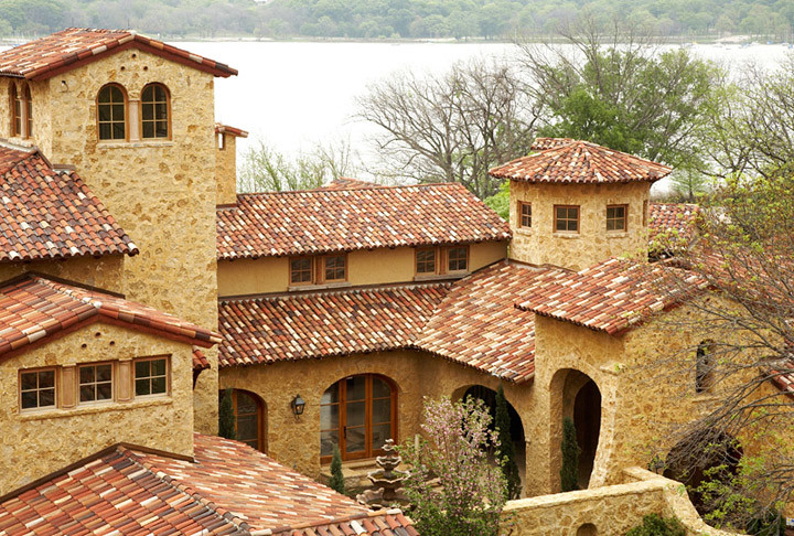 Large tuscan beige two-story stucco house exterior photo in San Diego with a hip roof and a tile roof